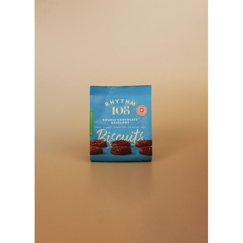 Rhythm 108 Unsere reichhaltigen und schokoladigen Haselnusskekse sind perfekt gebacken mit dunklen Kakaostückchen und Kokosnussöl. Doppelt so viel SCHOKOLADE und MILCHFREI. - Produktbild